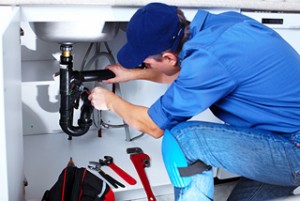 plumber making repairs under sink